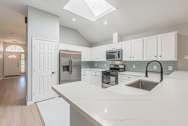 kitchen featuring kitchen peninsula, stainless steel appliances, light stone counters, and sink