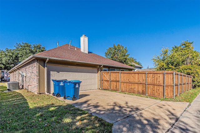 view of property exterior featuring central AC unit, a garage, and a lawn