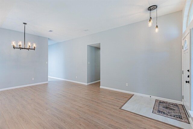 unfurnished room with light hardwood / wood-style flooring and an inviting chandelier