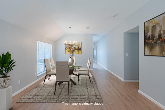 dining space with a chandelier, wood-type flooring, and vaulted ceiling