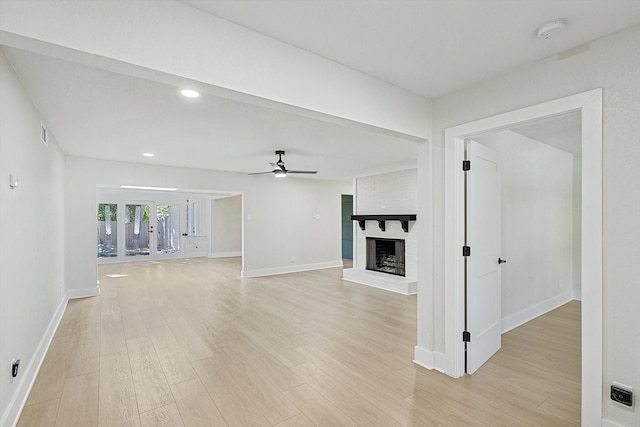 unfurnished living room featuring ceiling fan, a fireplace, and light hardwood / wood-style flooring