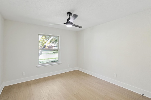 spare room featuring ceiling fan, light wood-type flooring, and a textured ceiling