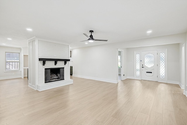 unfurnished living room with a brick fireplace, light hardwood / wood-style flooring, and ceiling fan