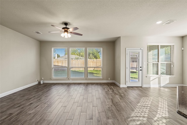 empty room featuring plenty of natural light, ceiling fan, and wood-type flooring