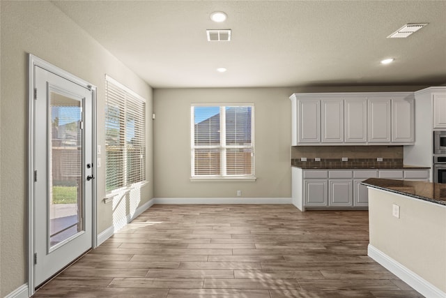 kitchen with white cabinetry, hardwood / wood-style floors, stainless steel appliances, and a textured ceiling