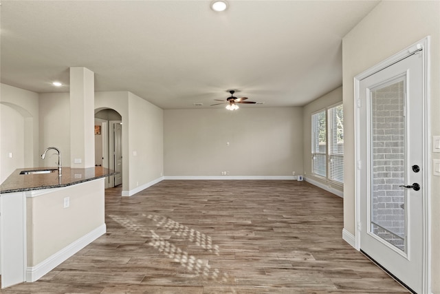 unfurnished living room featuring ceiling fan, light wood-type flooring, and sink