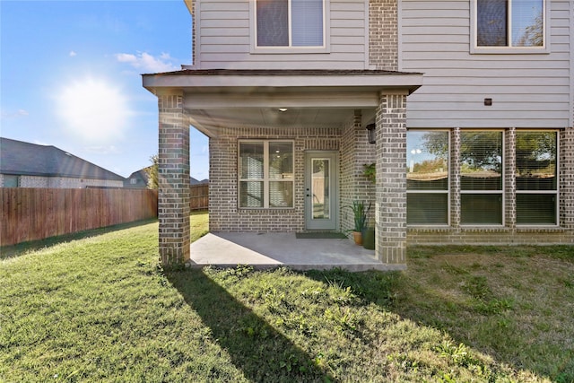 view of exterior entry featuring a yard and a patio