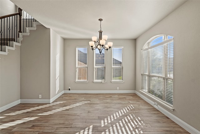 unfurnished dining area with wood-type flooring and a chandelier