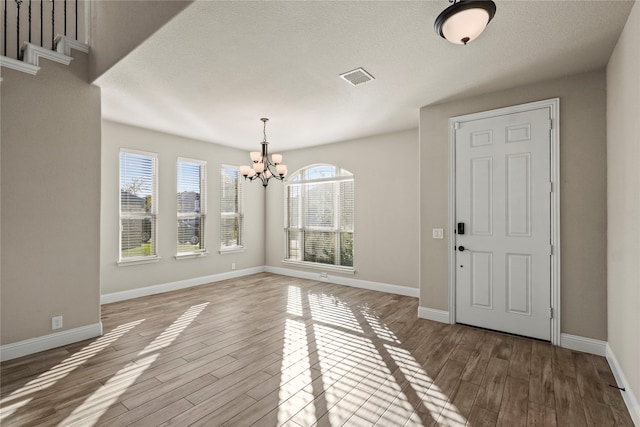 foyer featuring a textured ceiling, hardwood / wood-style flooring, and a notable chandelier