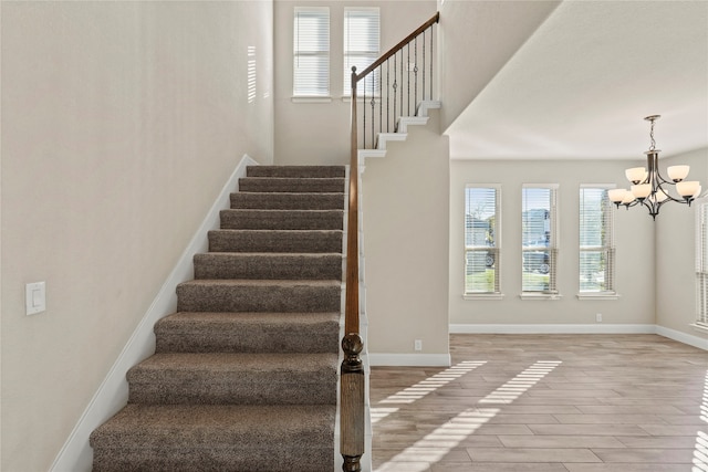 staircase with hardwood / wood-style flooring and a chandelier