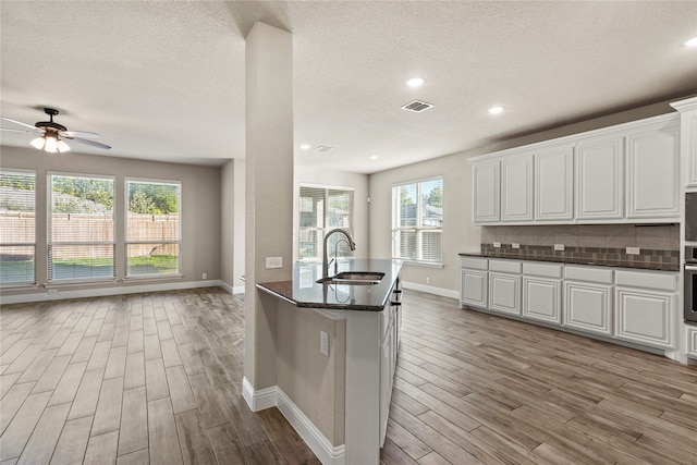 kitchen featuring white cabinetry, sink, a healthy amount of sunlight, and light hardwood / wood-style flooring