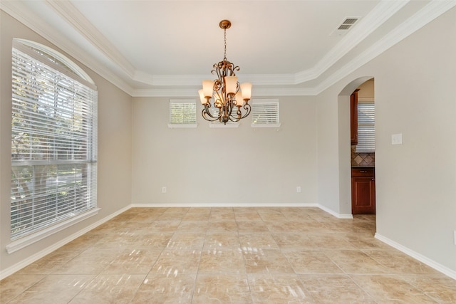 empty room with a chandelier, a tray ceiling, and ornamental molding