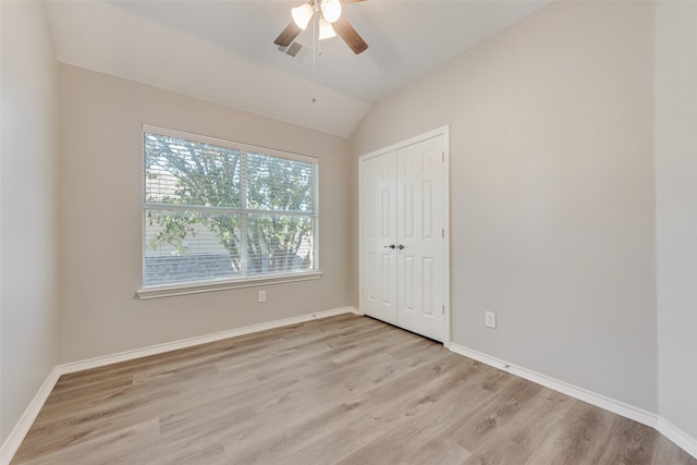 spare room with ceiling fan, vaulted ceiling, and light wood-type flooring