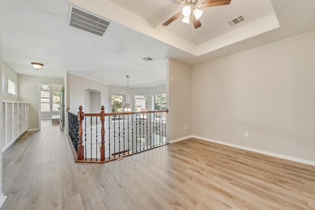 unfurnished room featuring a tray ceiling, ceiling fan with notable chandelier, and hardwood / wood-style flooring