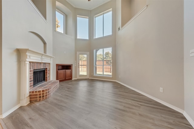 unfurnished living room featuring a fireplace, a high ceiling, and light hardwood / wood-style flooring