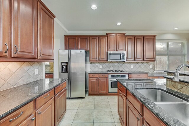 kitchen featuring sink, crown molding, decorative backsplash, light tile patterned floors, and appliances with stainless steel finishes