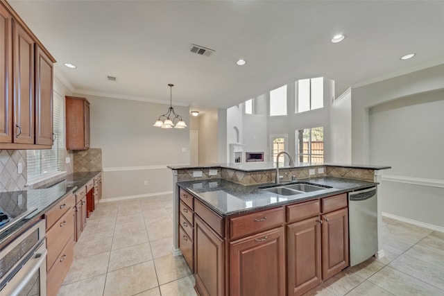 kitchen with sink, a kitchen island with sink, a chandelier, decorative backsplash, and appliances with stainless steel finishes