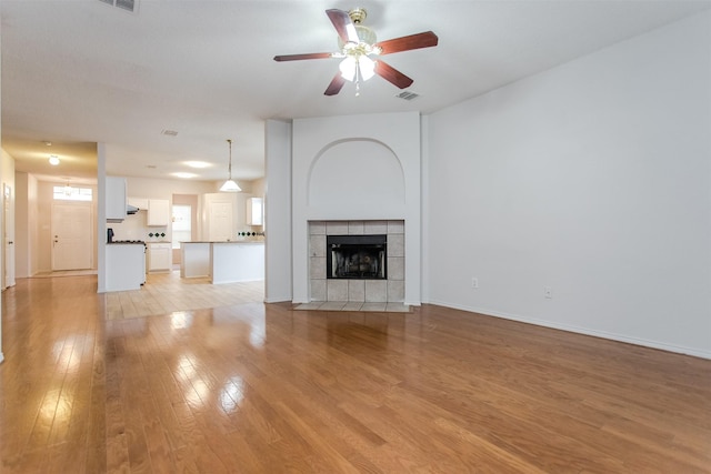 unfurnished living room with a fireplace, light wood-type flooring, and ceiling fan