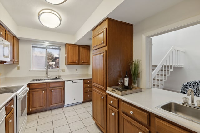 kitchen with light tile patterned floors, white appliances, and sink