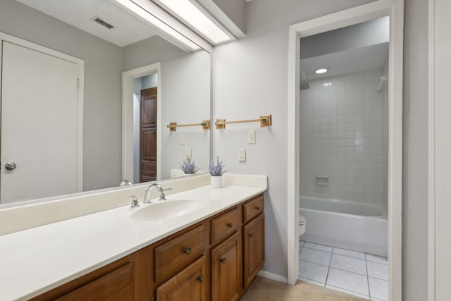 full bathroom featuring tile patterned floors, tiled shower / bath, vanity, and toilet