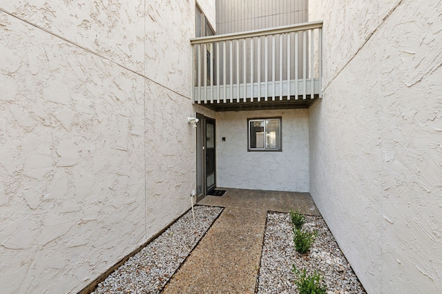 view of exterior entry with a balcony