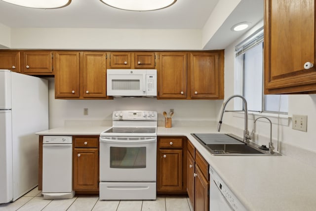 kitchen featuring sink, light tile patterned floors, and white appliances