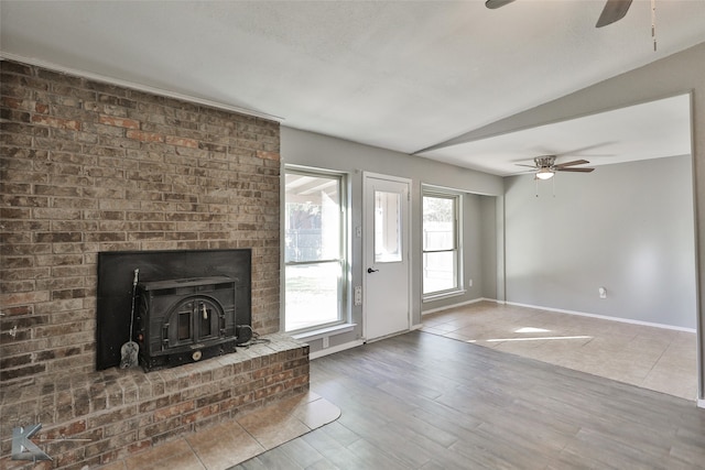 unfurnished living room with a wood stove, ceiling fan, hardwood / wood-style floors, and lofted ceiling