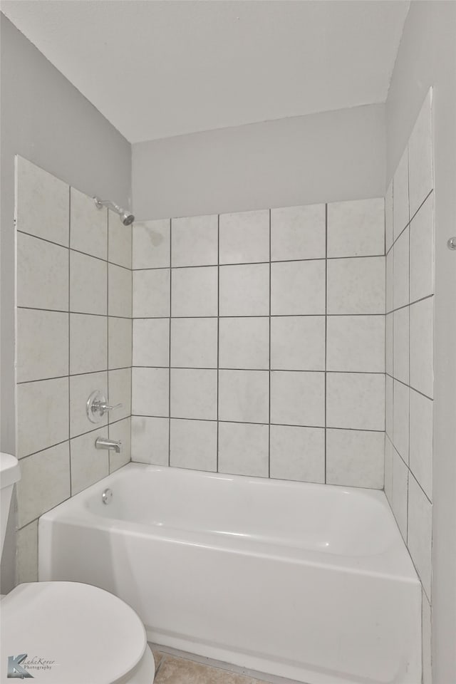 bathroom with toilet and tiled shower / bath