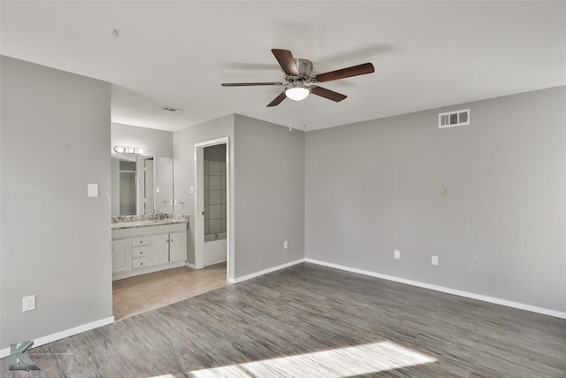 unfurnished bedroom with ensuite bathroom, ceiling fan, and light hardwood / wood-style floors