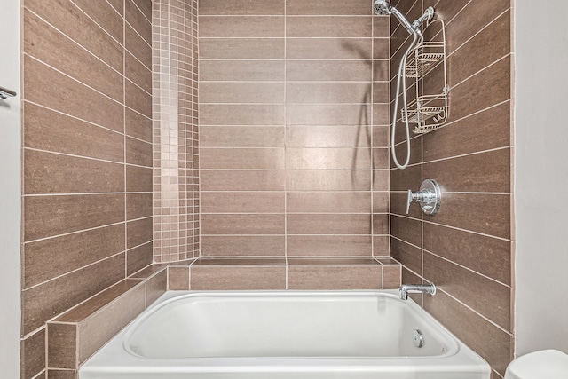 bathroom featuring tiled shower / bath combo and toilet