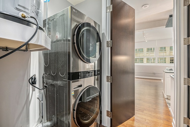 laundry room with light hardwood / wood-style flooring and stacked washer and clothes dryer