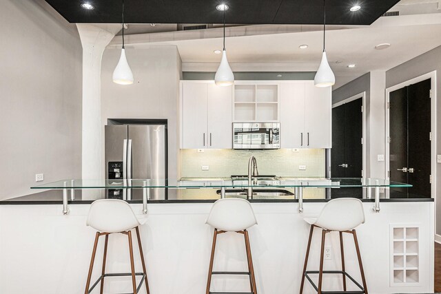 kitchen featuring white cabinetry, a breakfast bar, hanging light fixtures, and appliances with stainless steel finishes