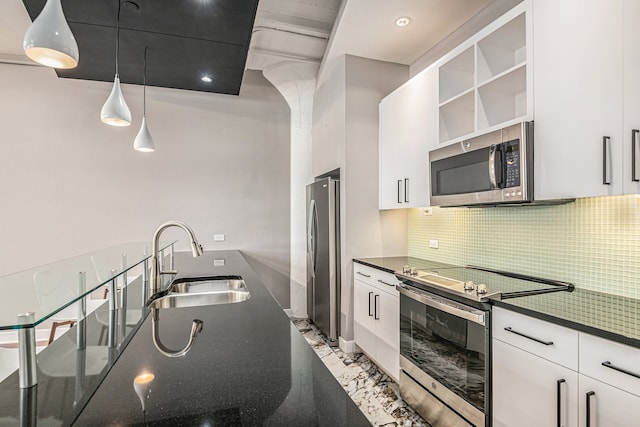 kitchen featuring tasteful backsplash, stainless steel appliances, sink, decorative light fixtures, and white cabinetry