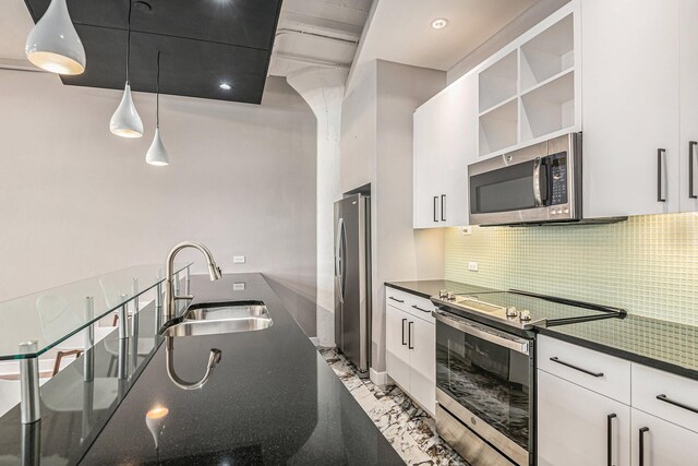 kitchen featuring tasteful backsplash, stainless steel appliances, sink, decorative light fixtures, and white cabinetry