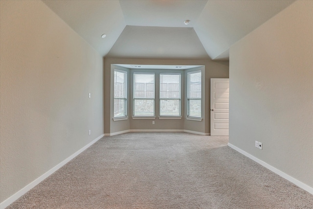 carpeted empty room featuring lofted ceiling