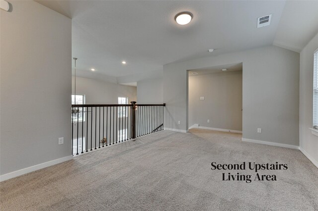 empty room featuring light colored carpet and vaulted ceiling