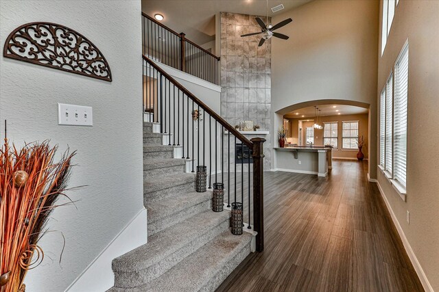 unfurnished living room featuring a tile fireplace, dark hardwood / wood-style floors, and a high ceiling