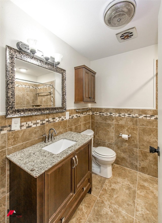 bathroom with a shower with curtain, vanity, toilet, and tile walls