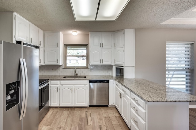 kitchen featuring sink, white cabinets, stainless steel appliances, and light hardwood / wood-style floors