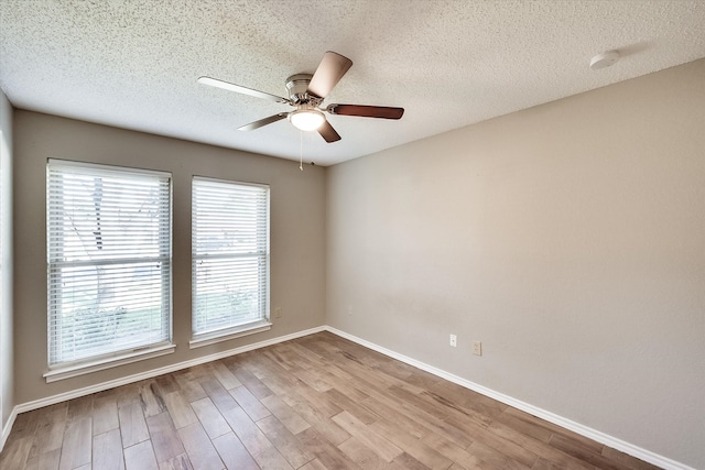 empty room featuring a textured ceiling, light wood-type flooring, and ceiling fan