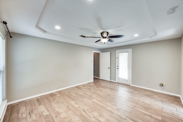 spare room featuring ceiling fan, light wood-type flooring, and a textured ceiling