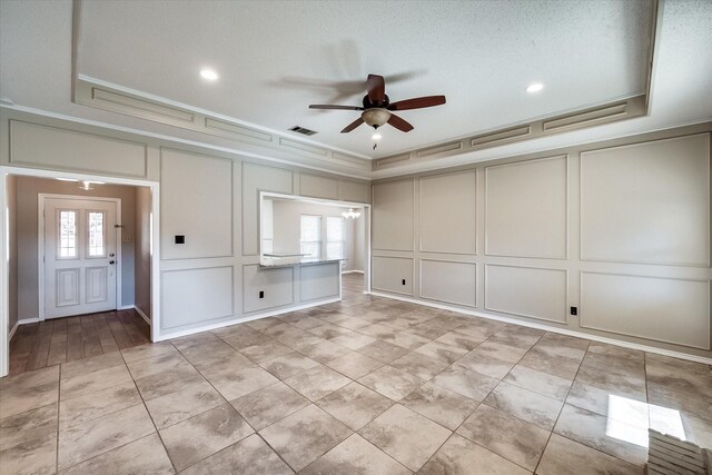 unfurnished room with ceiling fan, ornamental molding, a textured ceiling, and a tray ceiling