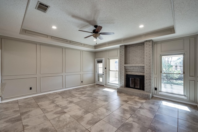 unfurnished living room with a tray ceiling, a wealth of natural light, and ceiling fan