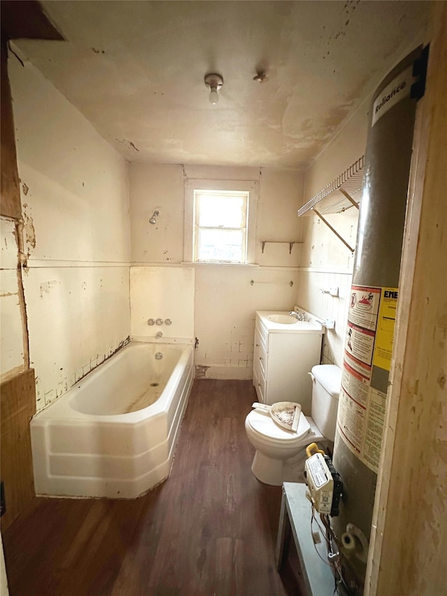 bathroom with a tub to relax in, vanity, water heater, hardwood / wood-style flooring, and toilet