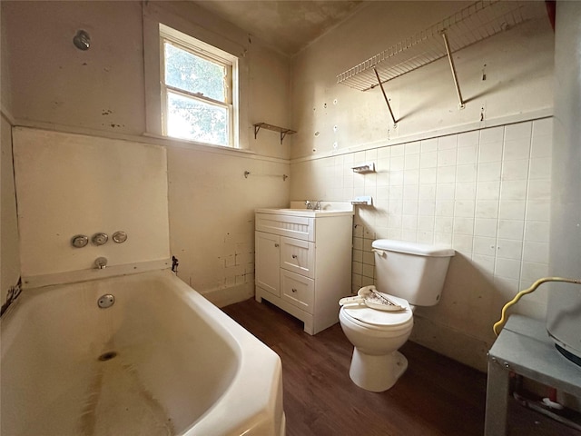 bathroom featuring vanity, wood-type flooring, tile walls, toilet, and a bathing tub