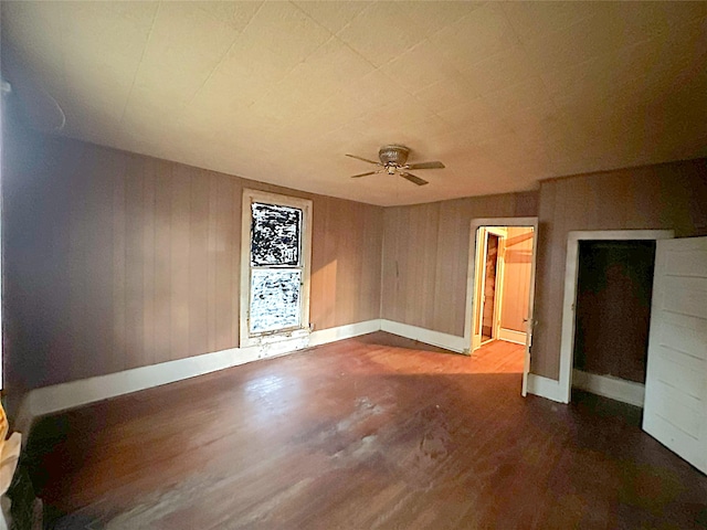 unfurnished room with ceiling fan, wood walls, and hardwood / wood-style flooring