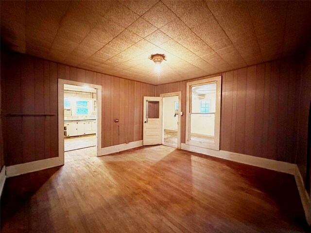 empty room featuring hardwood / wood-style flooring and wood walls