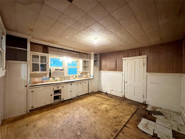 kitchen featuring white cabinetry, cooling unit, and wooden walls