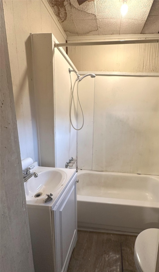 full bathroom with vanity, hardwood / wood-style flooring, washtub / shower combination, toilet, and wood walls