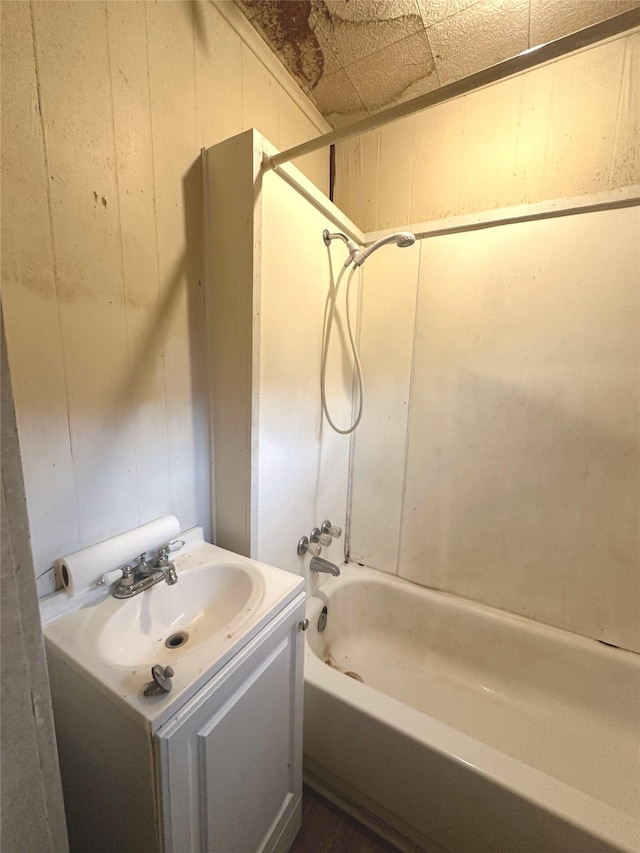 bathroom featuring vanity, shower / washtub combination, and wooden walls